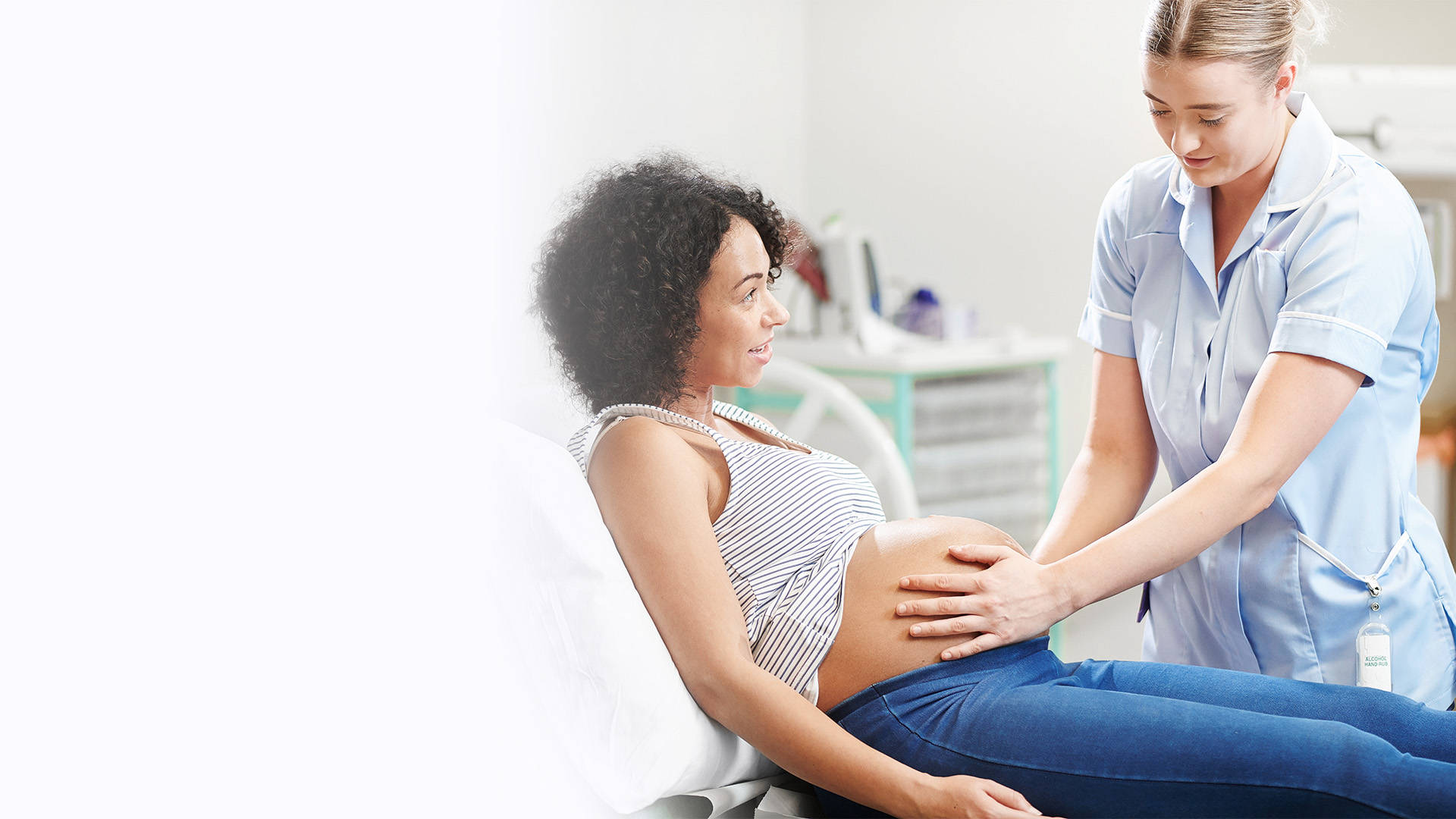 Eine Hebamme von ilomed untersucht eine schwangere Frau