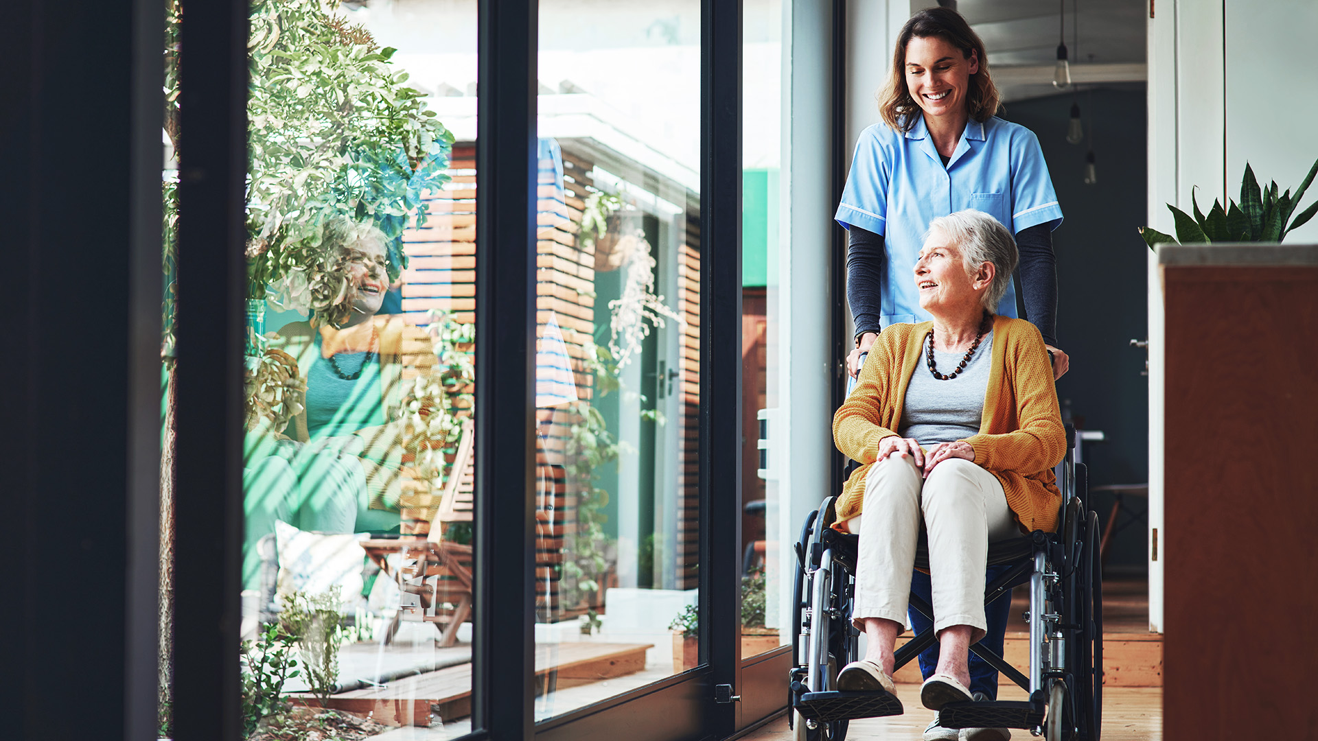 ilomed Pflegekraft schiebt eine ältere Dame im Rollstuhl ilomed Pflegekraft schiebt eine ältere Dame im Rollstuhl